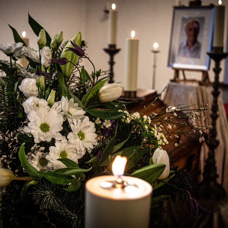 Aufgebahrte Sarg mit Blumen und Kerze